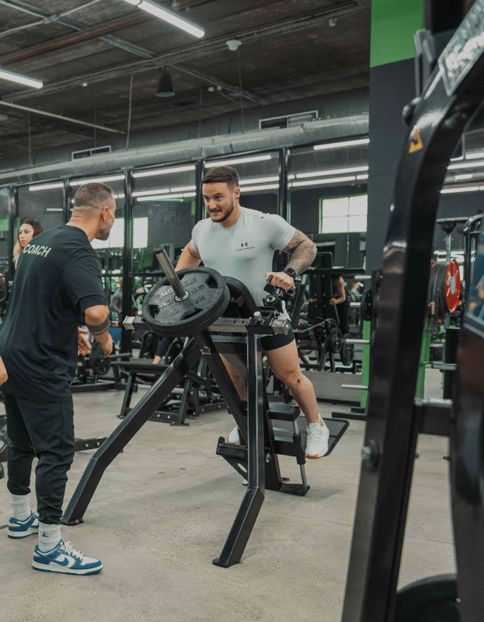 Personal trainer assisting client with weightlifting form