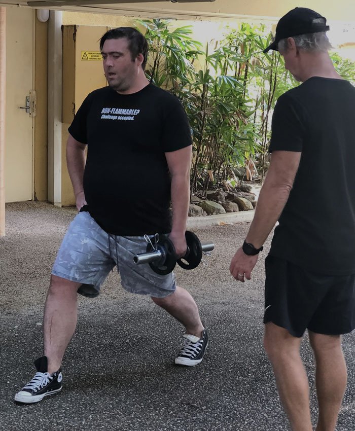 Personal trainer assisting client with weightlifting form